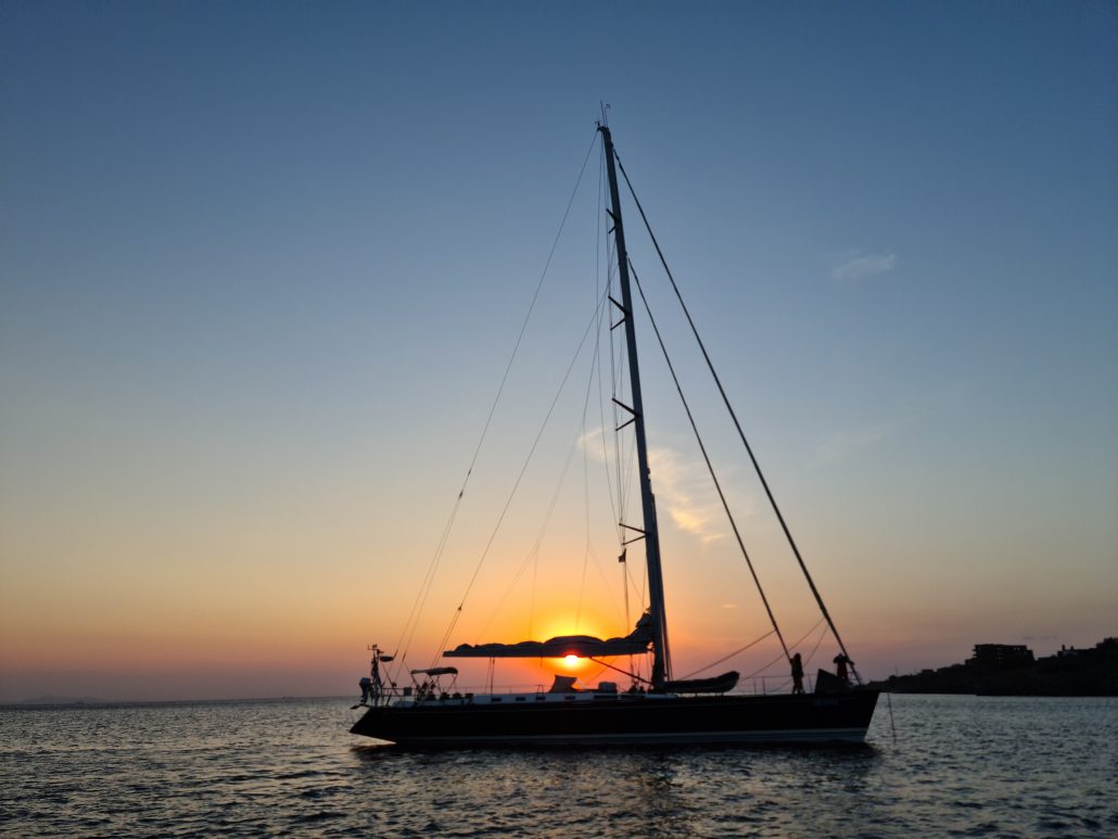 Silhouette of a schooner against a setting sun in Greece