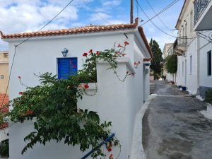 white house with blue door on winding path in Poros Greece