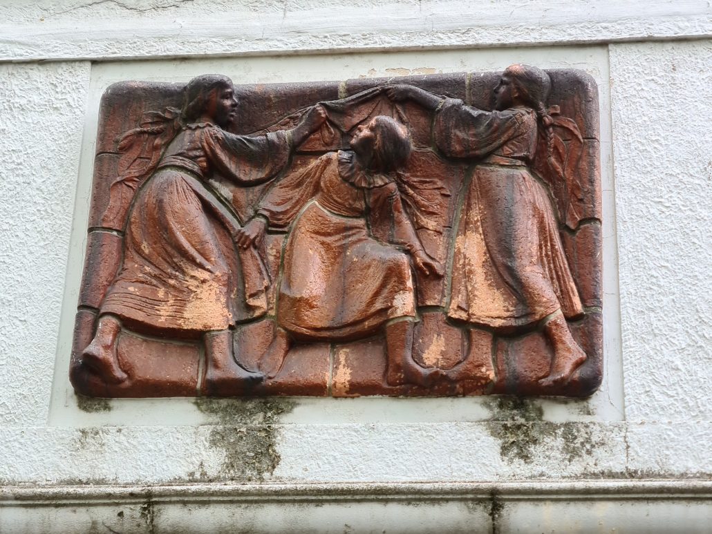 Bronze art work over the door of an aparment building in Bratislava showing three girls playing