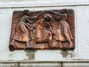 Bronze art work over the door of an aparment building in Bratislava showing three girls playing
