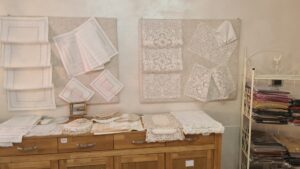 samples of lace pinned to a wall and laying on a wooden chest of drawers