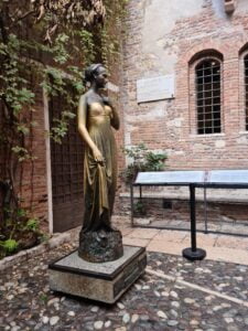 Life-sized bronze statue of a young woman (Juliet Montague) in a courtyard in Verona