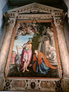 16th century oil painting showing a man holding a spade looking down on a kneeling woman. An angel is reflect in a window on the right and a couple walk in the background on the left - Noli me tangera by Montemezzano, Verona, Italy