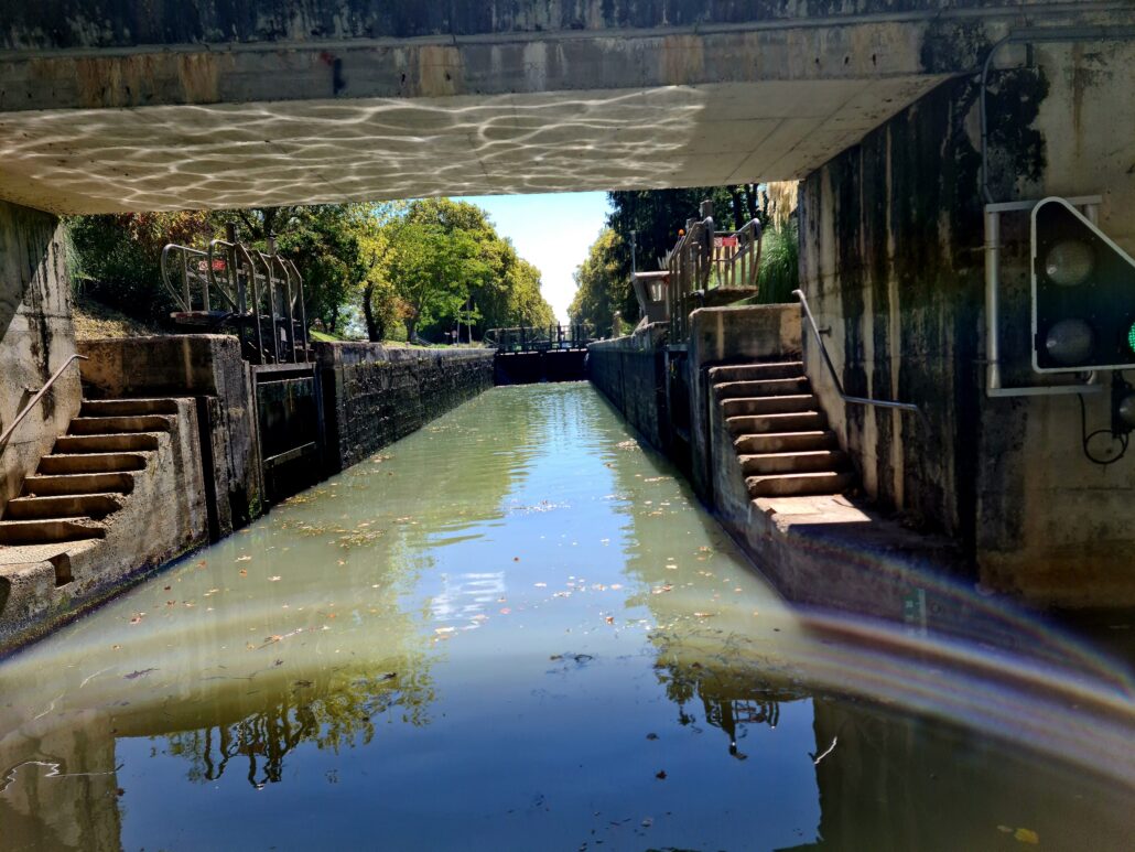 Entering a lock. Stone steps on either side leading to the bank of the canal. The lock in the distance. 