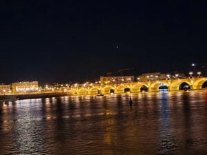 Multi-arched bridge spanning a wide river lit up at night