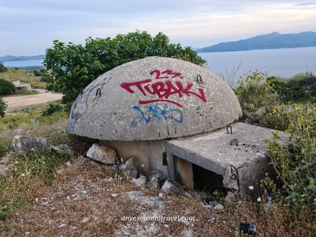 A mushroom-like concrete bunker with red graffiti that reads 23. Tubaki on a cliff overlooking the sea