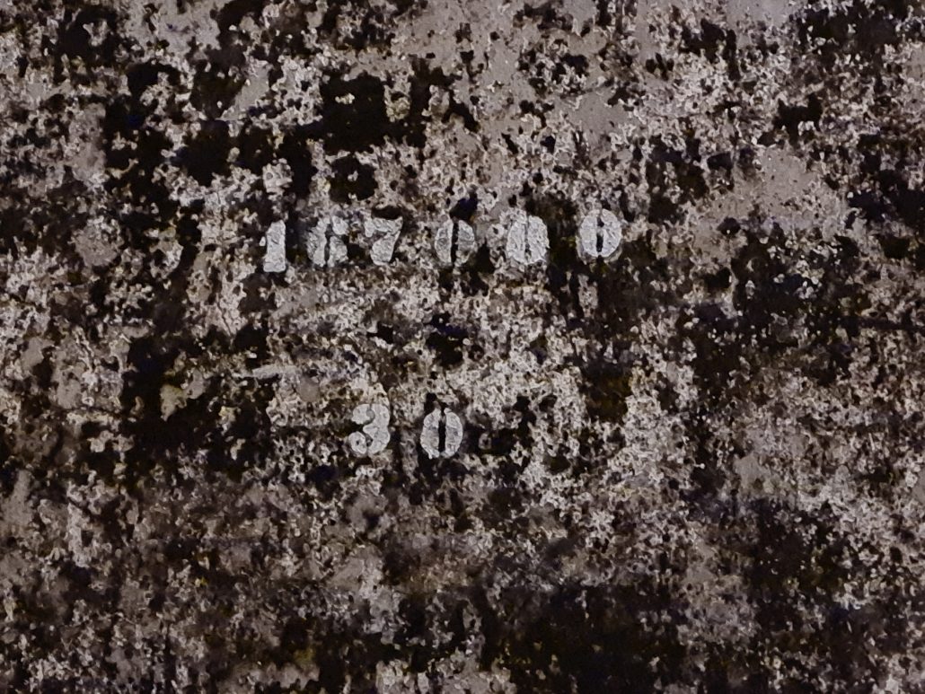 WAll covered in black mould with the numbers 167000 and 30 stencilled in white