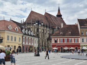 City square showing colourful baroque buildings down to sides and in the corner a massive gothic black church