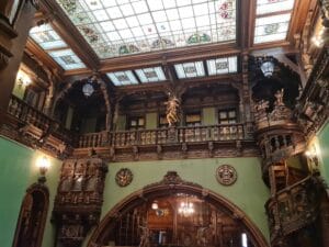 Interior of palace with stained glass ceiling and heavy dark wood trim on the green painted walls