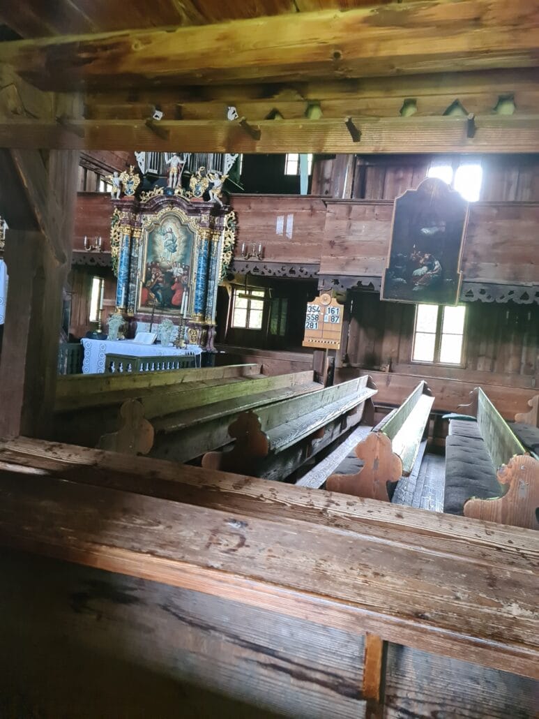 Interior of a wooden church seen through a window - wooden pews and an ornate altarpiece