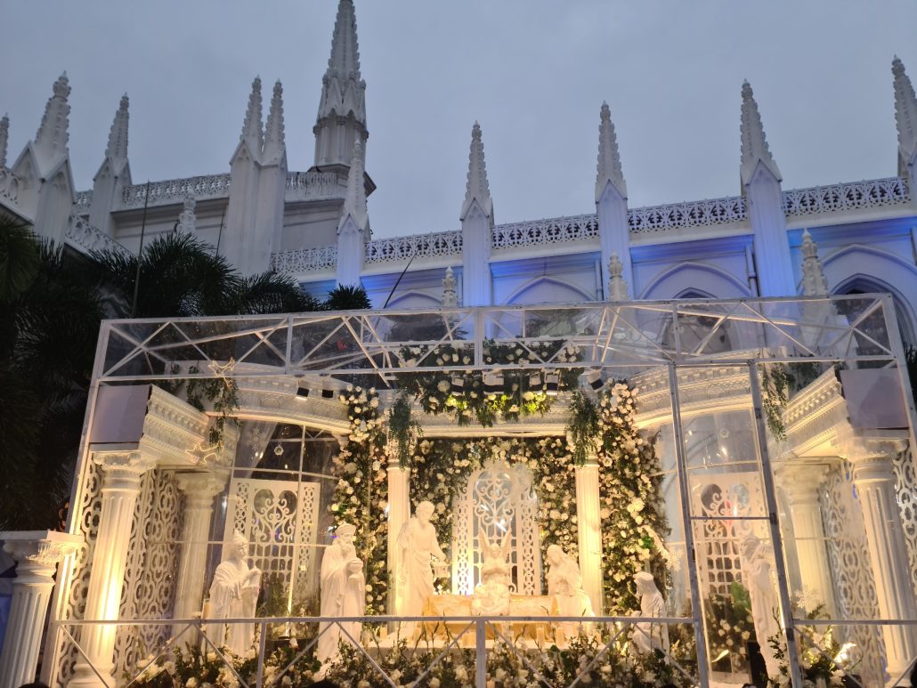 Huge nativity set in a glass casing, lit up in front of a white church
