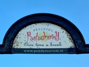 Semi-circular sign that reads Peaceful Puducherry - Give time a break