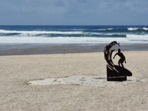 Metal sculpture of a surfer catching a wave ... on a beach in Portugal