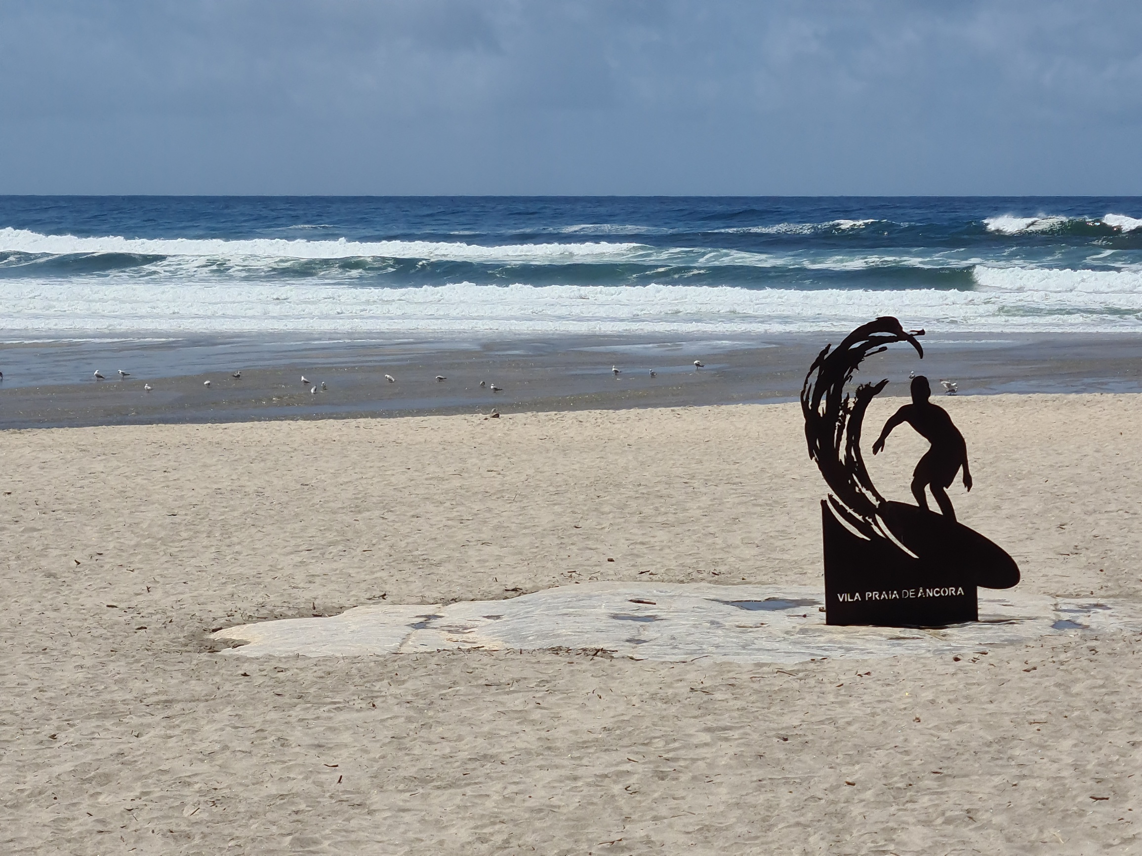 Metal sculpture of a surfer catching a wave ... on a beach in Portugal