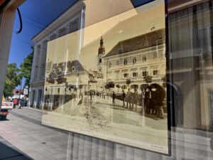 Old sepia photo of an old town square behind a windowpane on a street