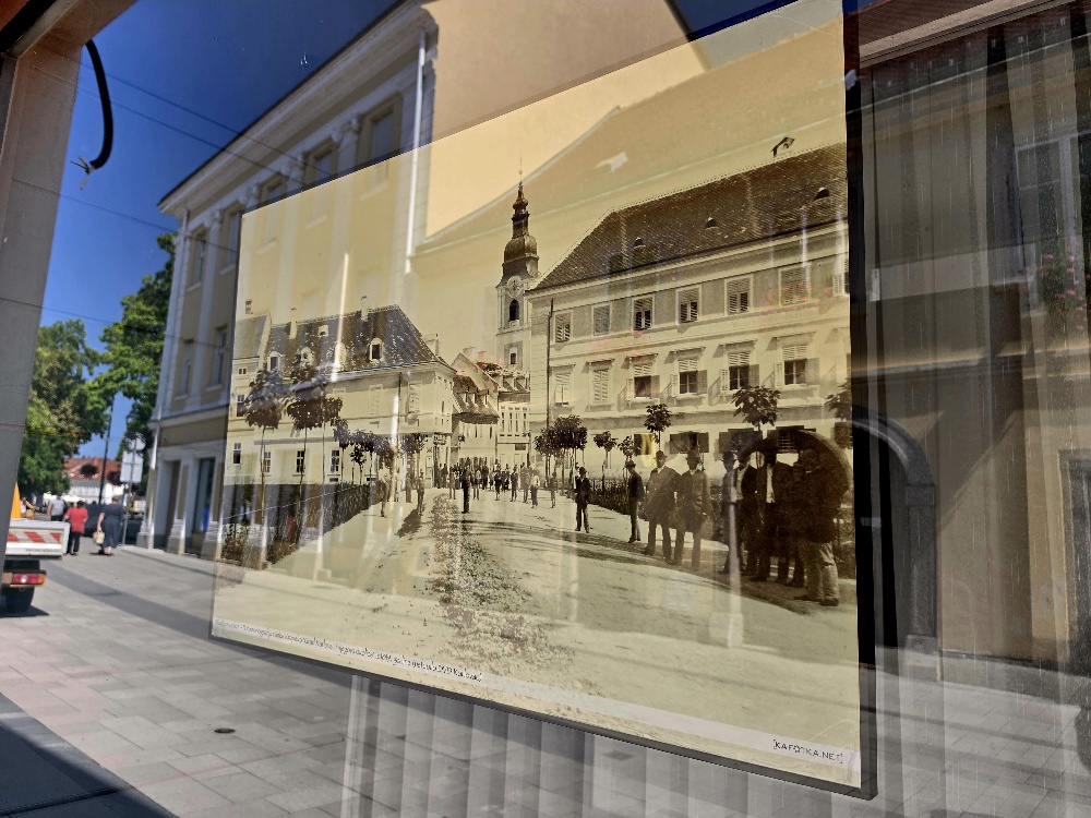 Old sepia photo of an old town square behind a windowpane on a street