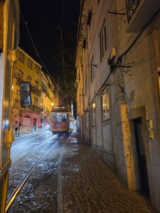 Old-fashioned yellow tram on a narrow cobblestone street at night
