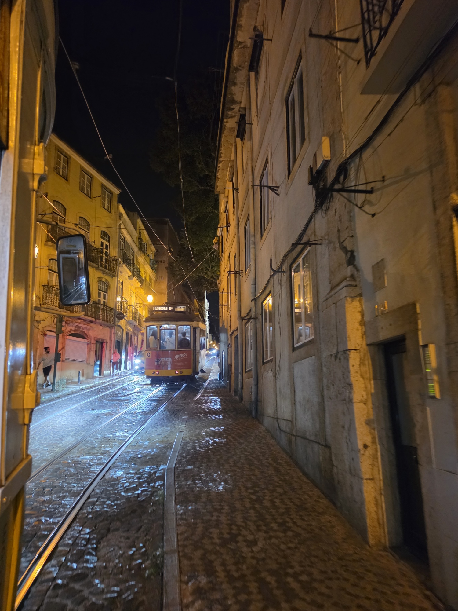 Old-fashioned yellow tram on a narrow cobblestone street at night