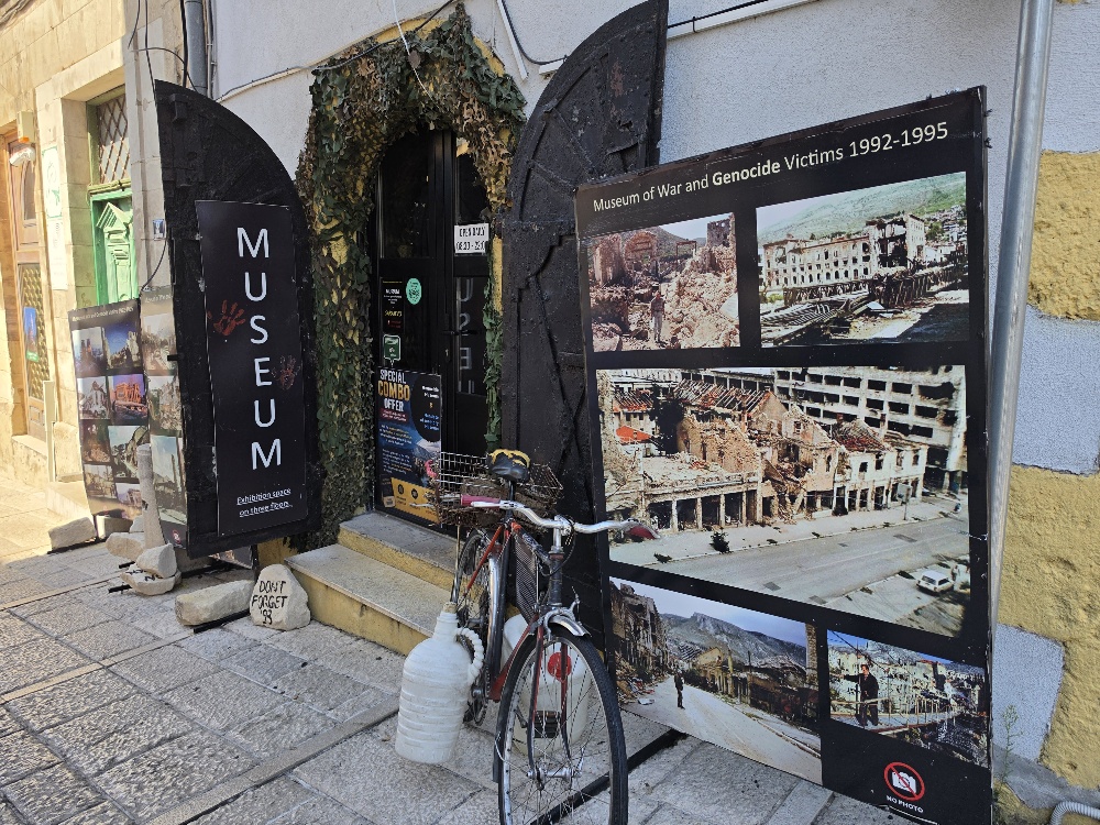 Entrance to the Museum of War and Genocide Victims 1992–1995 in Mostar, displaying photographs of wartime destruction in the city.