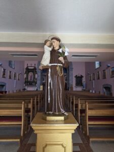 A statue of St Anthony of Padua holding the Christ Child inside an empty church,