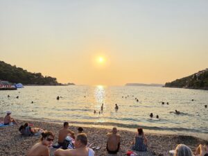 beginning of a sunset - pebble beach - people swimming and sunbathing